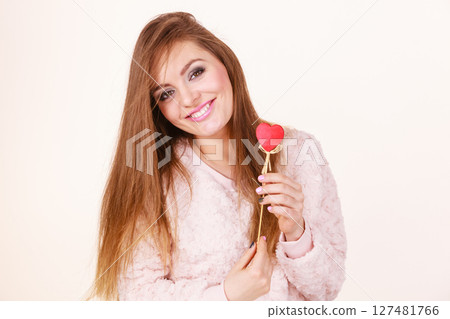 Flirty woman holding red wooden heart on stick Flirty woman holding red wooden heart on stick 127481766