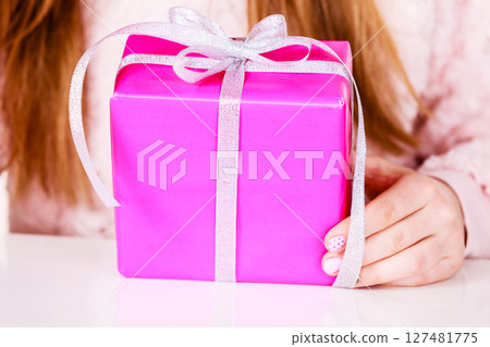 Female hands holding pink gift box with ribbon 127481775