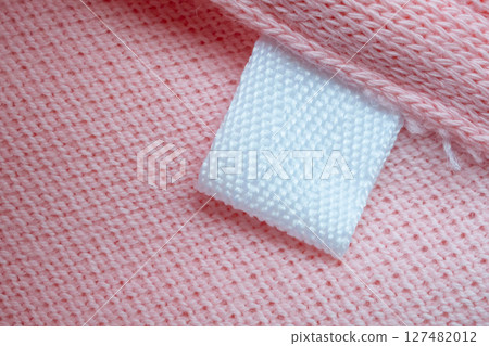 White blank laundry care clothes label on pink shirt fabric background 127482012