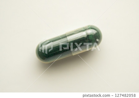 Green herbal medicine capsule on white background 127482058