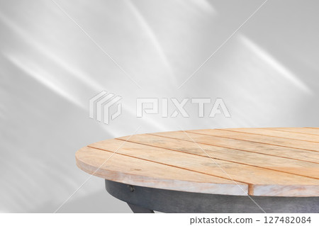 Round wood table top with abstract shadow drop on white wall background for mockup product display 127482084
