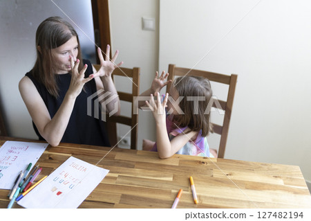 Mother and daughter communicating using sign language at home 127482194