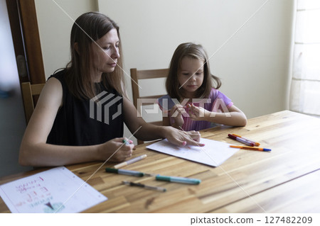 Mother helping daughter with homework, homeschooling, early childhood education Mother helping daughter with homework, homeschooling, early childhood education 127482209