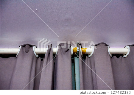 Curtain rod with gray curtains attached to a light purple wall 127482383