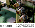 Three dusty spools of thread attached to an old industrial machine 127482385