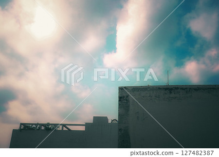 Rooftop silhouette under a vibrant sky with scattered clouds Rooftop silhouette under a vibrant sky with scattered clouds 127482387