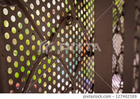Perforated metal sheet with colorful blurred light background Perforated metal sheet with colorful blurred light background 127482389