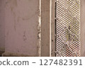 Close up of a weathered white wall next to a perforated metal sheet 127482391