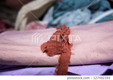 Close-up of stacked colorful fabrics with a frayed textile strip 127482393