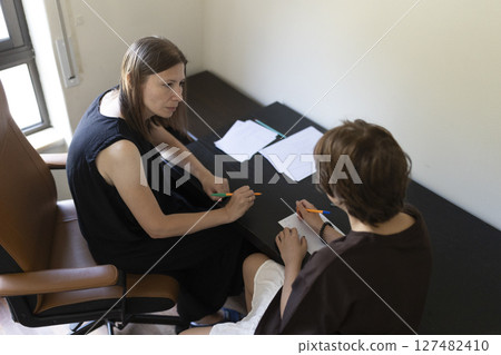 Teacher helping student with test preparation in classroom Teacher helping student with test preparation in classroom 127482410