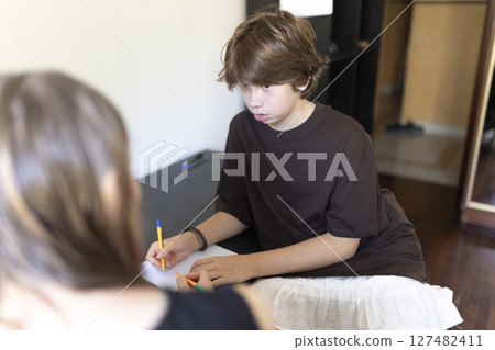 Boy drawing with colored pencils during homeschooling session with tutor Boy drawing with colored pencils during homeschooling session with tutor 127482411