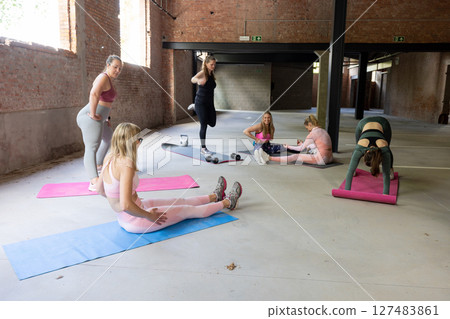 A Group of Women Actively Engaged in Various Fitness Activities Inside a Spacious Indoor Setting 127483861