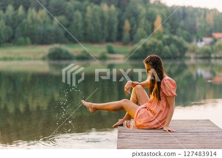 Woman Splashing Water On Lake Pier Woman Splashing Water On Lake Pier 127483914