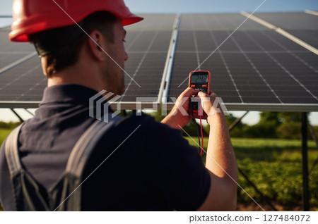 Measuring the electricity by using device. Man is doing operating and maintenance in solar power plant 127484072