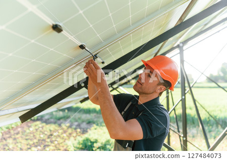 Fixes the wires. Man is doing operating and maintenance in solar power plant 127484073
