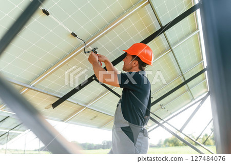 Fixes the wires. Man is doing operating and maintenance in solar power plant 127484076