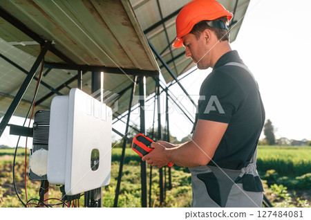 Checking the temperature by thermal imager. Man is doing operating and maintenance in solar power plant 127484081