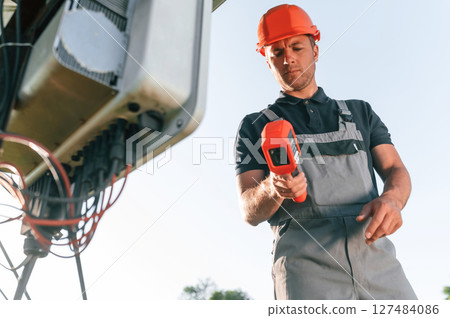 Checking the temperature by thermal imager. Man is doing operating and maintenance in solar power plant Checking the temperature by thermal imager. Man is doing operating and maintenance in solar power plant 127484086