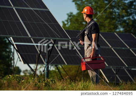 Red repair toolbox is in hands. Man is doing operating and maintenance in solar power plant 127484095