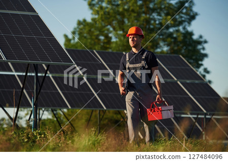 Red repair toolbox is in hands. Man is doing operating and maintenance in solar power plant 127484096