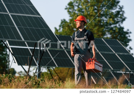 Red repair toolbox is in hands. Man is doing operating and maintenance in solar power plant Red repair toolbox is in hands. Man is doing operating and maintenance in solar power plant 127484097