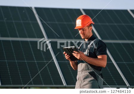 Tablet in hands. Man is doing operating and maintenance in solar power plant Tablet in hands. Man is doing operating and maintenance in solar power plant 127484110