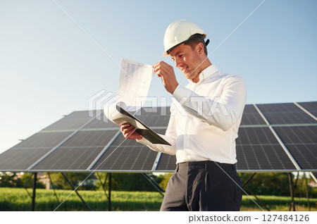 Notepad with document is in hands. Man is doing operating and maintenance in solar power plant 127484126