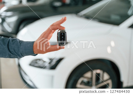 Hand is holding the keys. Close up view of man that is with electrical car 127484430