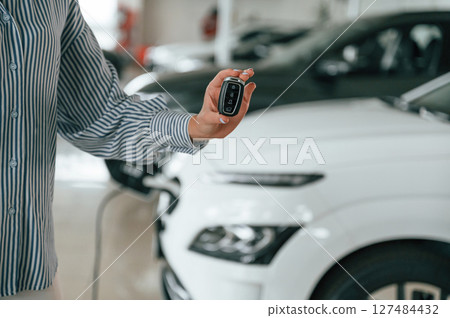 Hand is holding the keys. Close up view of man that is with electrical car Hand is holding the keys. Close up view of man that is with electrical car 127484432
