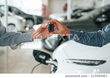 Man in formal clothes is with woman customer with the electric car Man in formal clothes is with woman customer with the electric car 127484461