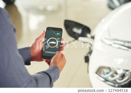 Charging process on the smartphone app. Close up view of man that is with electrical car Charging process on the smartphone app. Close up view of man that is with electrical car 127484516