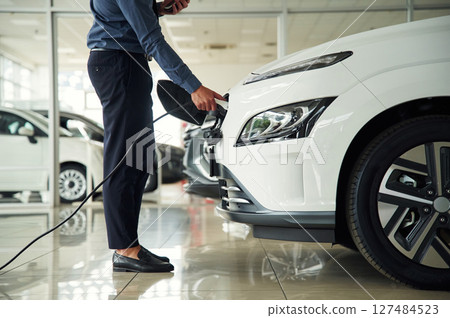 Putting charger into electrical car socket. Close up view of man 127484523