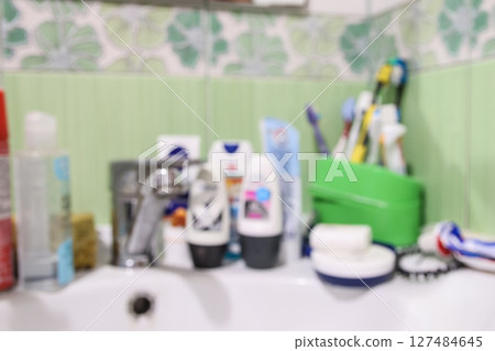 A blurred and messy bathroom sink, featuring an antiperspirant, toothbrush, toothpaste, and soap near the faucet. Bathroom mess on a sink with a blurred background 127484645