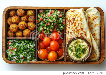Falafel wrap, tabbouleh salad and hummus dip in a wooden lunch box. Middle Eastern lunch box. 127485196