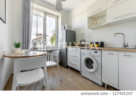 Bright Modern Kitchen with Window and Round Table 127485207