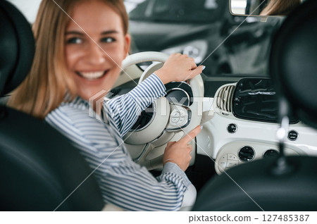 Driving the automobile. Beautiful woman is indoors with the modern car Driving the automobile. Beautiful woman is indoors with the modern car 127485387