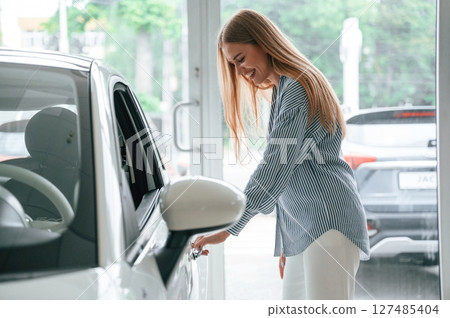 Beautiful woman is indoors with the modern car Beautiful woman is indoors with the modern car 127485404