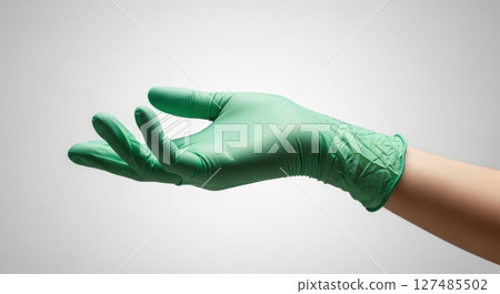 Hand wearing a green disposable medical glove with an open palm gesture 127485502