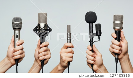 Hands holding a variety of microphones for professional audio and media production 127485516