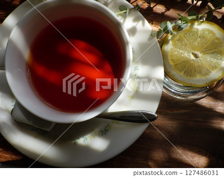 A cup of hot tea with lemon and sugar cubes on a sunny table 127486031