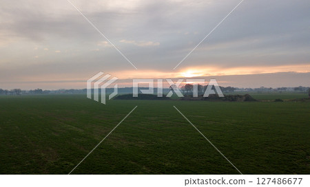 Aerial view on a dramatic and colorful sunrise or sunset sky over a grassy green farmfield shot from Aerial view on a dramatic and colorful sunrise or sunset sky over a grassy green farmfield shot from 127486677