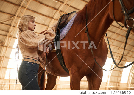 Taking care of animal. Beautiful young woman is with horse indoors 127486940