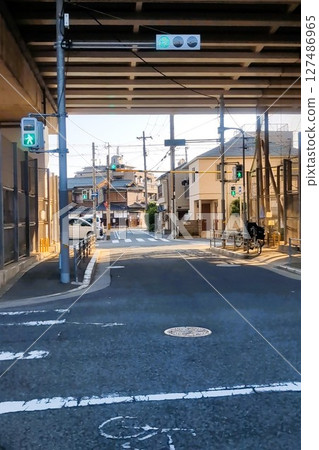 A deserted intersection under an overpass on a sunny day with traffic lights and signposts A deserted intersection under an overpass on a sunny day with traffic lights and signposts 127486965