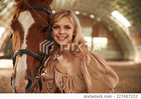 Portrait of beautiful young woman that is with horse indoors 127487222