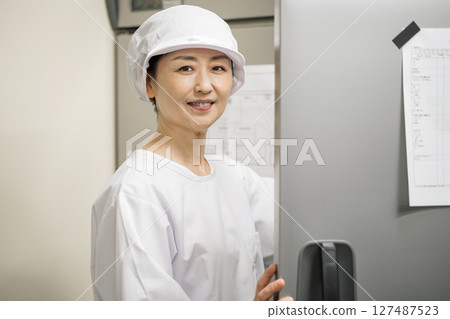 A woman in her 50s working at a food factory 127487523