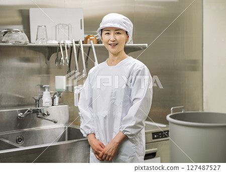 一名 50 多歲的女性在學校午餐中心的廚房工作 一名 50 多歲的女性在學校午餐中心的廚房工作 127487527