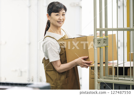 一位 50 多歲女性在物流倉庫工作的肖像 127487550