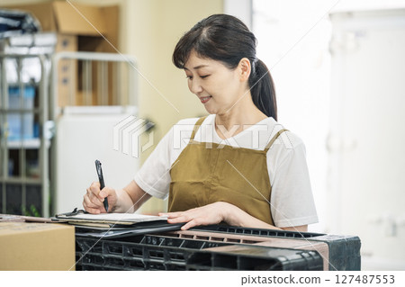 A middle-aged woman checking receipts in the back yard 127487553