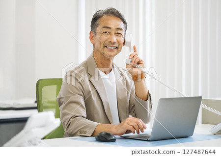 Senior man in his 60s making a phone call in the office 127487644