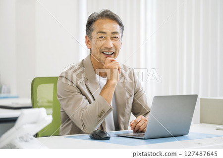 Senior man in his 60s doing desk work in the office Senior man in his 60s doing desk work in the office 127487645